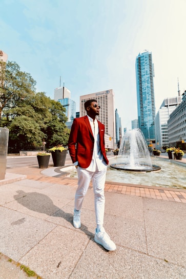 A stylish man wearing a sharp red jacket from Apex Trading, standing confidently against a city backdrop.