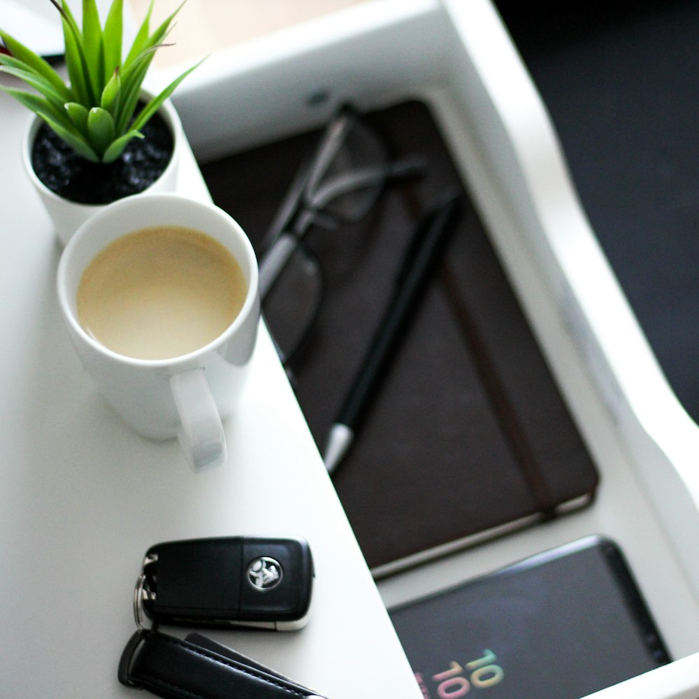 full mug beside white vehicle fob on white table