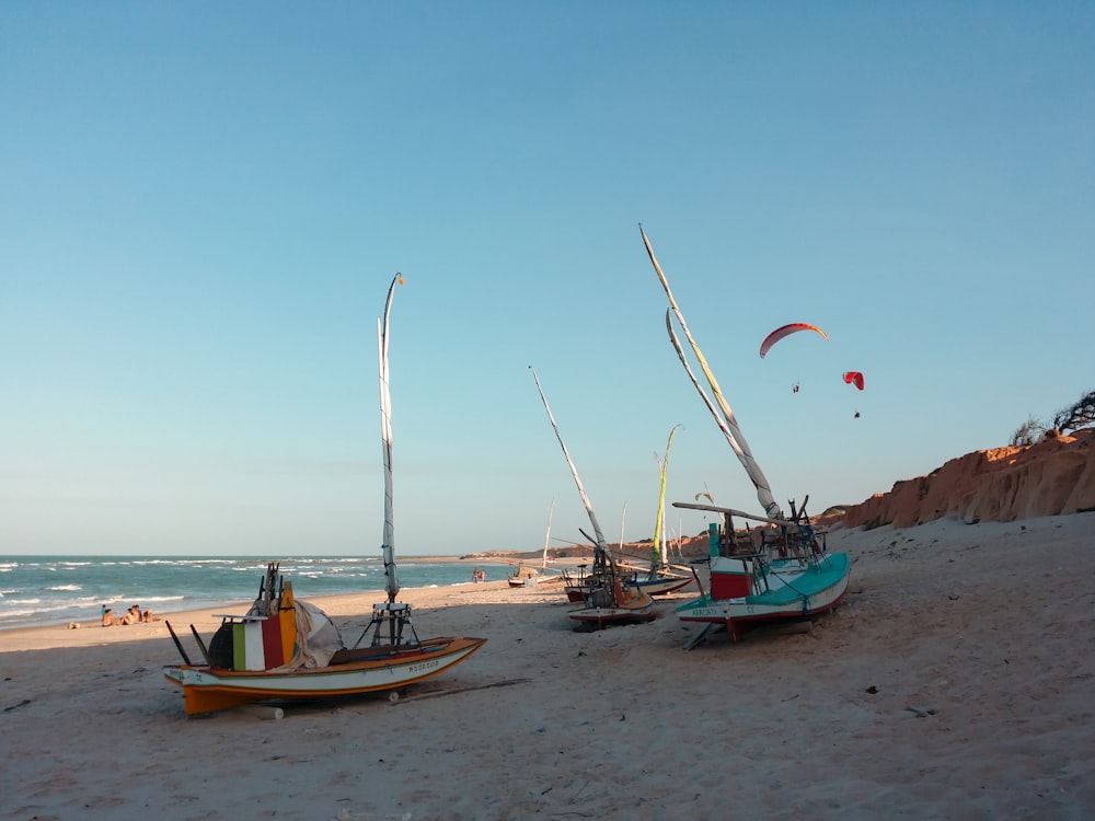 three white boats on seashore during daytime