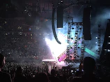 Drone shot of a packed concert stage with dynamic lighting and enthusiastic crowd.