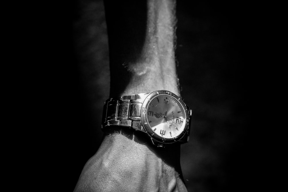 grayscale photography of person wearing round analog watch