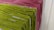 Racks of pasta are hanging side by side, with varying colors indicating different types or flavors. The pasta is neatly arranged and appears to be freshly made, showcasing green and pink hues.