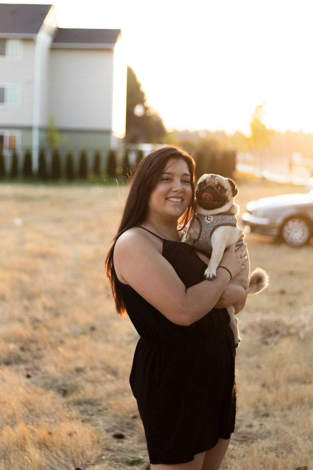 smiling woman holding pug during daytime