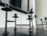 Black metal candle holders are placed on a dark wooden surface. Above them, a flat-screen television is affixed to a white wall. A power cable is visible extending down from the television.