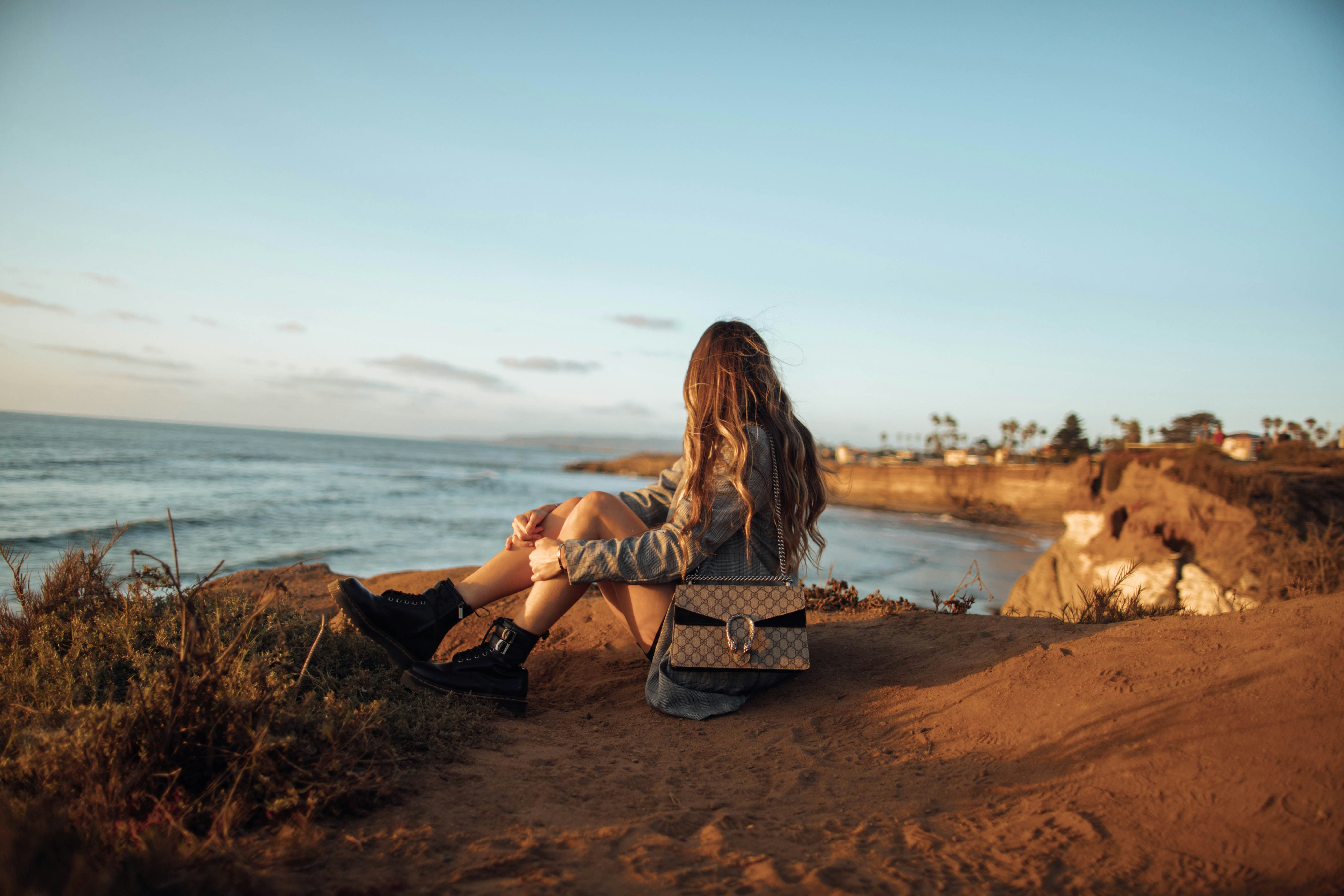 woman sitting on ground near body of water