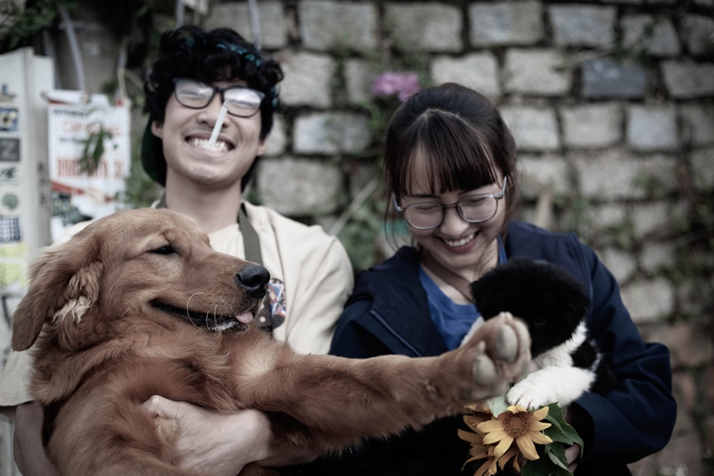 two smiling woman and man while carrying dog