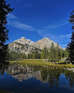 A serene landscape shot of mountains reflected in a still lake at dawn.