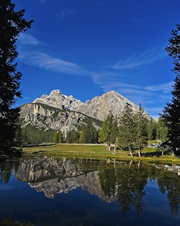 A serene landscape shot of mountains reflected in a still lake at dawn.