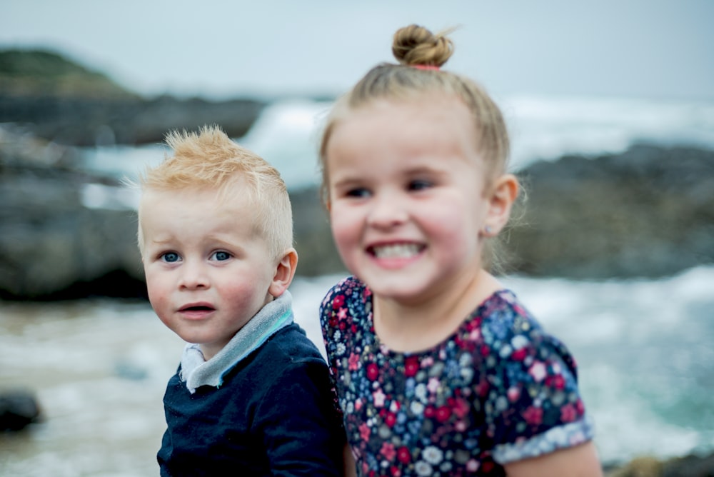 selective focus photography of girl and boy beside seashore during daytime