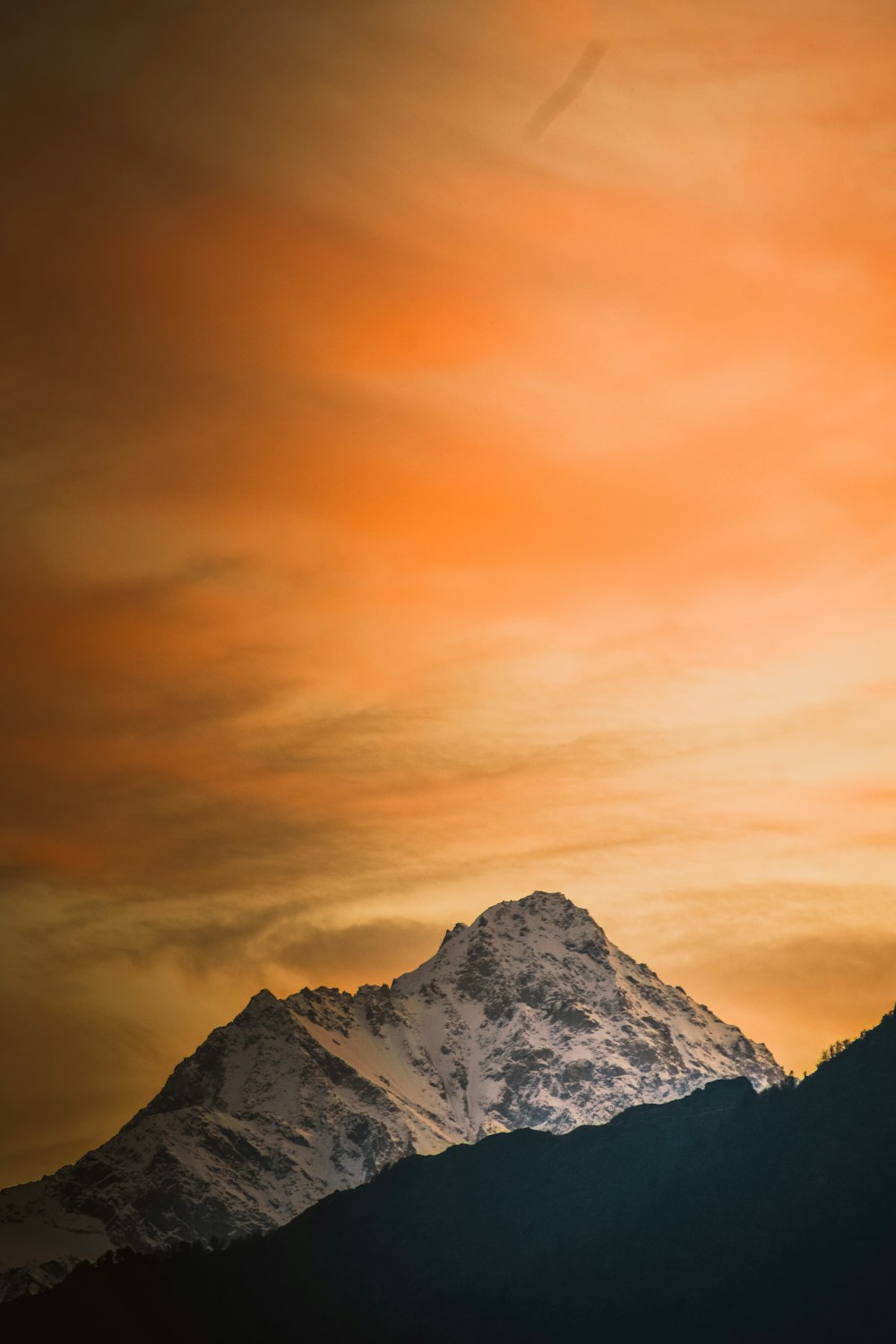 mountain covered with snow under orange sky