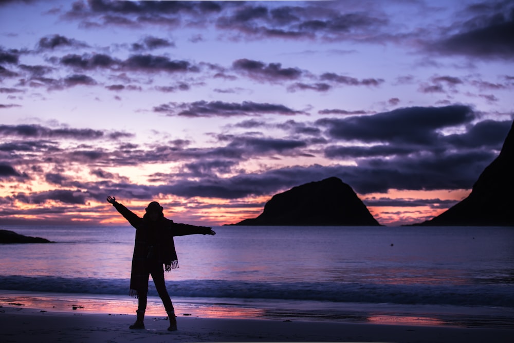 silhouette photography of woman standing on shore