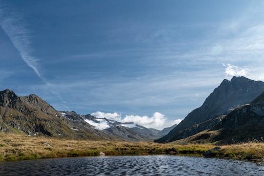 body of water, grass field, and mountains during day in Gotthardpass Switzerland