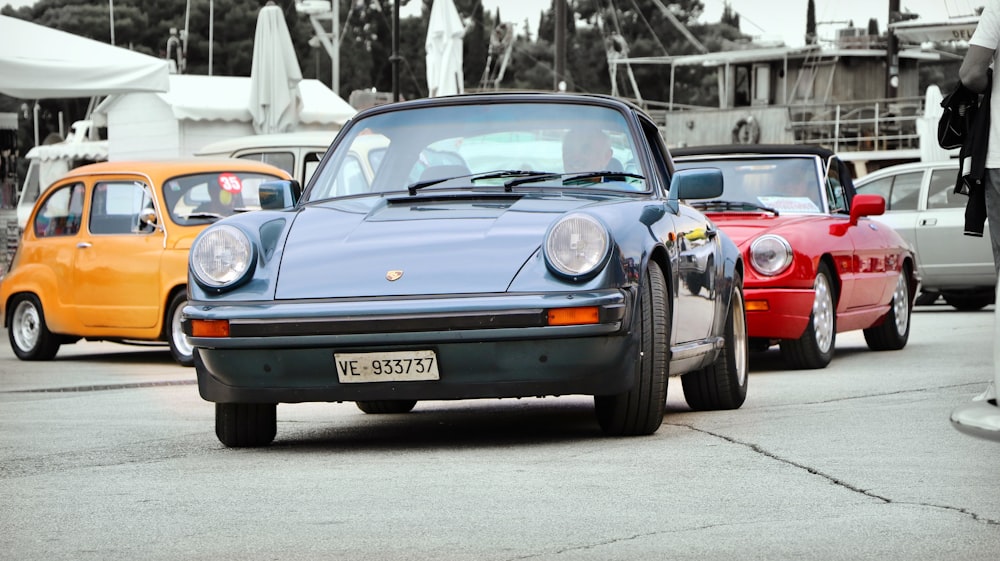 gray porsche coupe in front of red porsche coupe at daytime