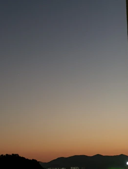 A serene twilight landscape with soft purple and orange hues behind mountain silhouettes.