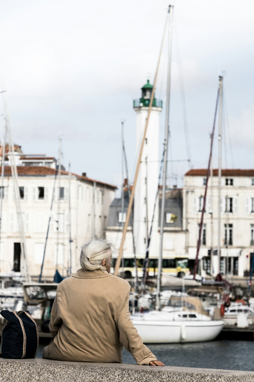 a person sitting on a wall looking at boats