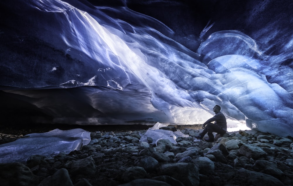 man sitting on rock near body of water during night time