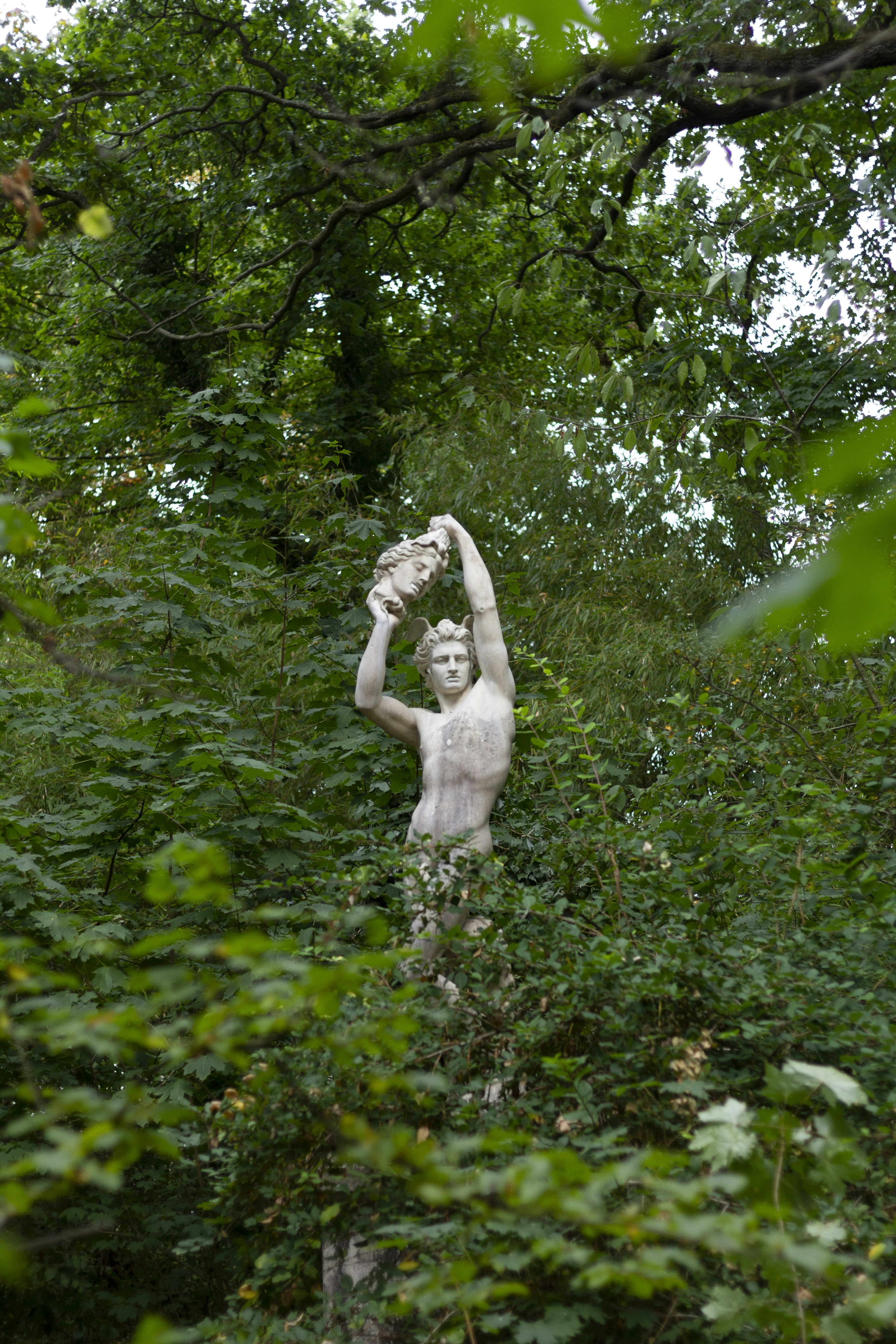 Estatua masculina rodeada de árboles