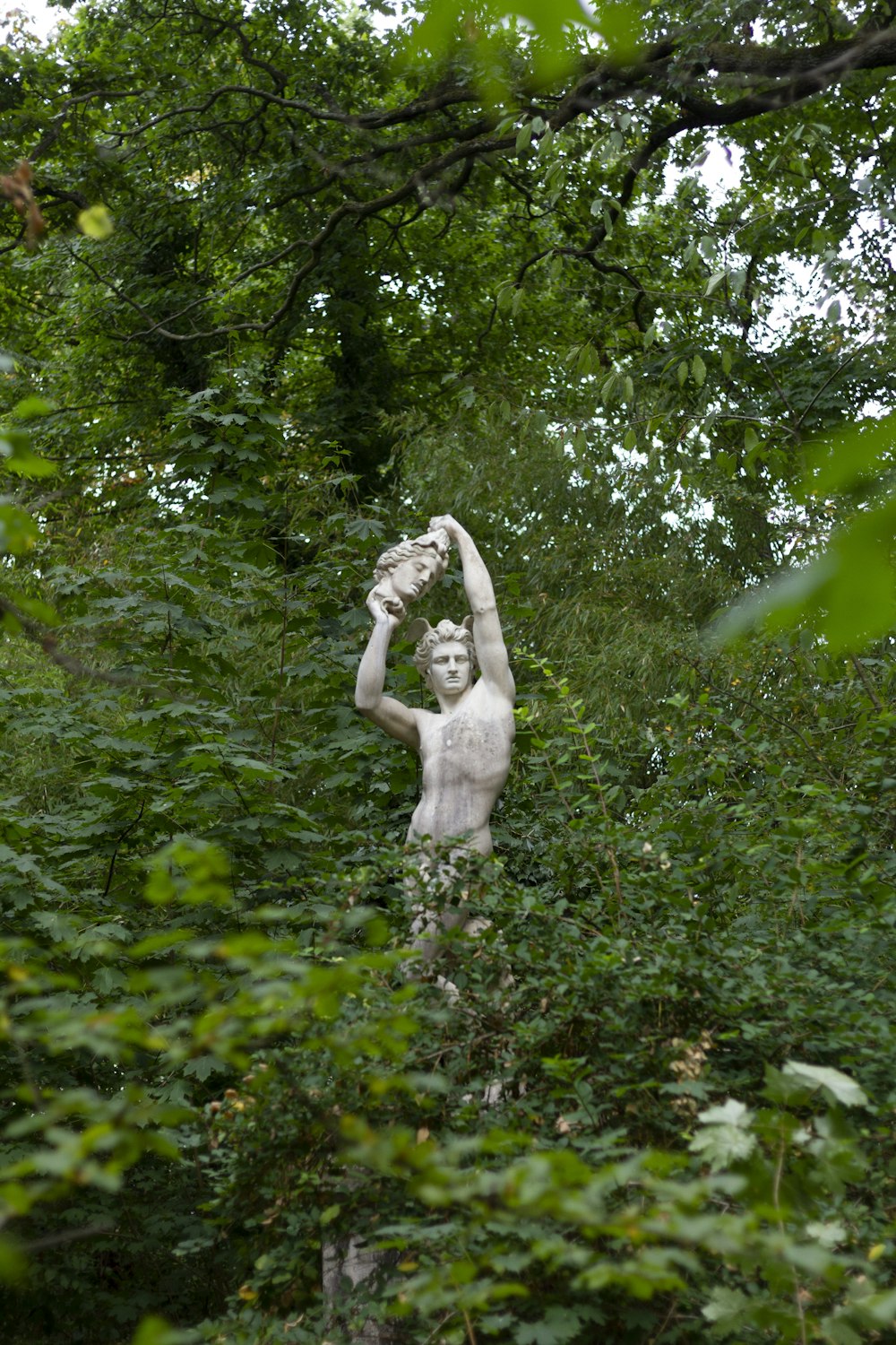 male statue surrounded by trees
