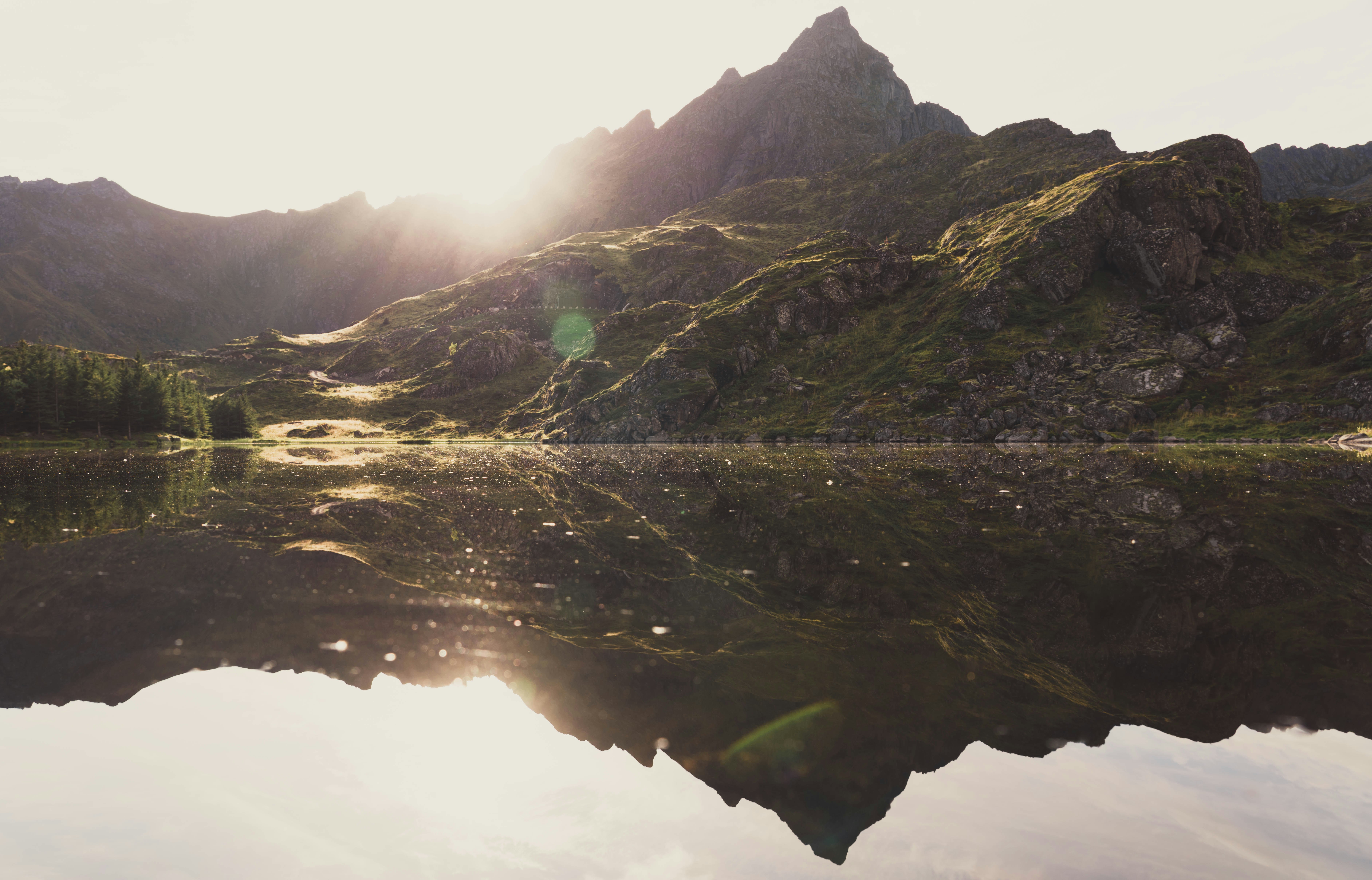 reflection of a green mountain on body of water