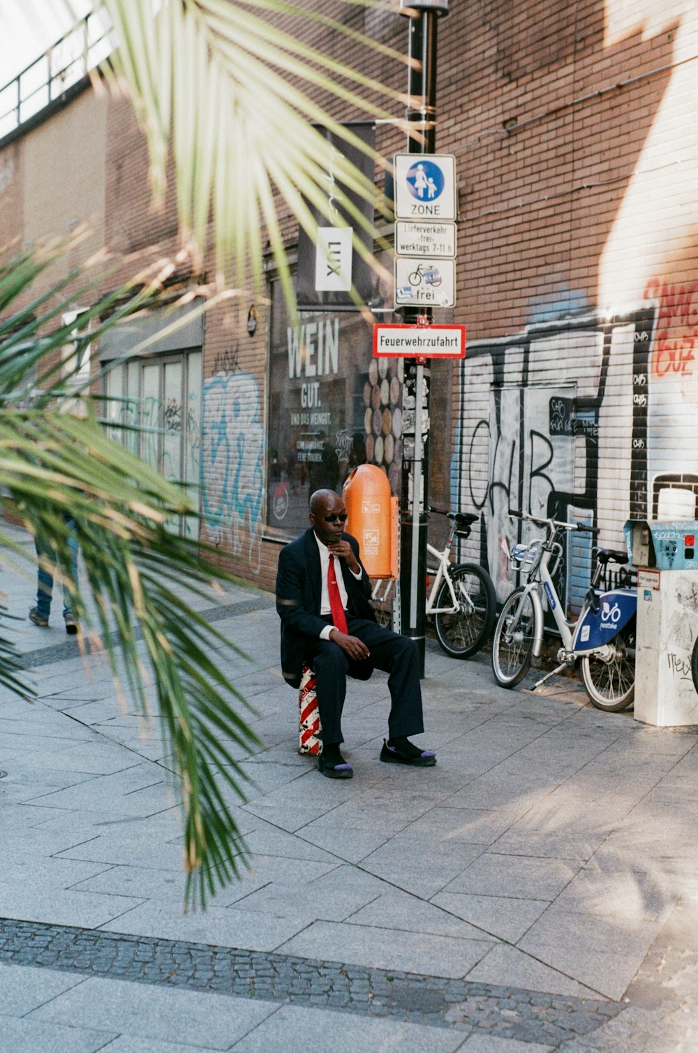 man in black jacket and black pants walking on sidewalk during daytime