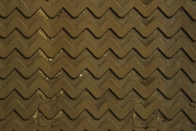 Close-up of textured safety floor mats in a busy factory aisle.