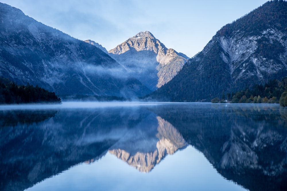 calm body of water near mountain