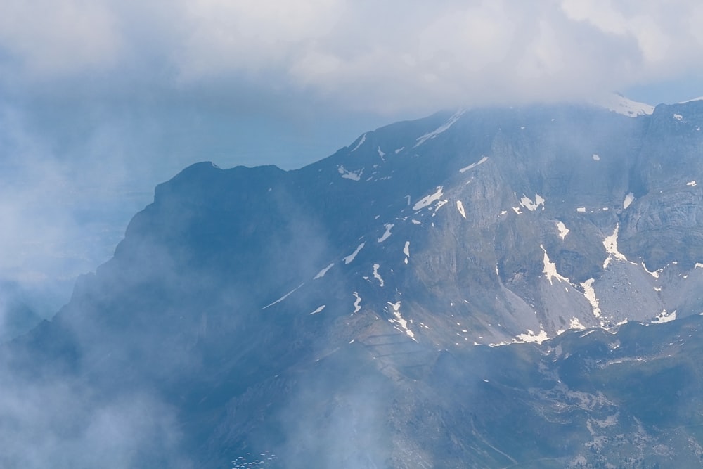 Photographie aérienne d’une montagne recouverte de neige sous un ciel blanc et bleu pendant la journée