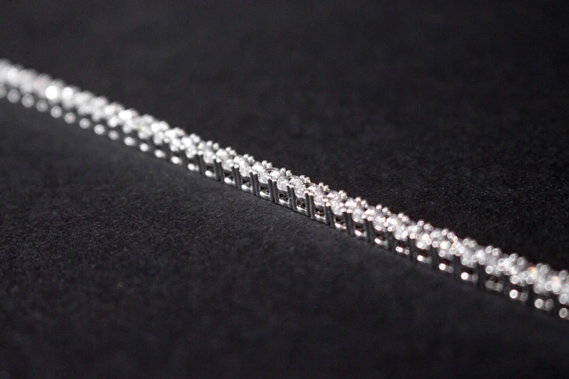 Line of round diamonds in a tennis bracelet on black fabric