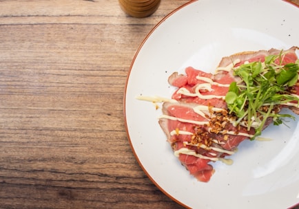 Close-up of a fresh, sizzling Adana kebap served on a black plate with fresh herbs.