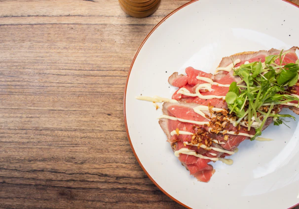 Close-up of a juicy filé steak plated with a vibrant lime-yellow sauce, garnished with fresh herbs.