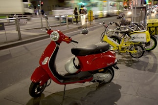 A sleek electric scooter parked beside a modern city street with glowing lights at dusk.