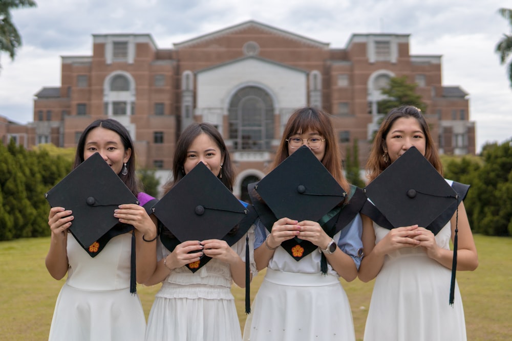 four women holding caps