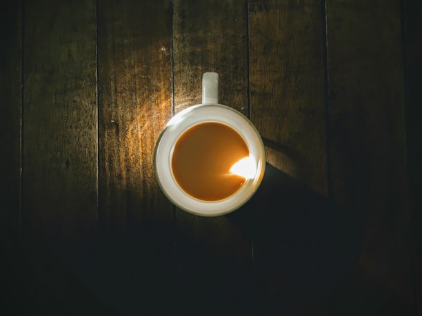 An artistic close-up of a custom coffee mug resting on a rustic wooden table with soft morning light.