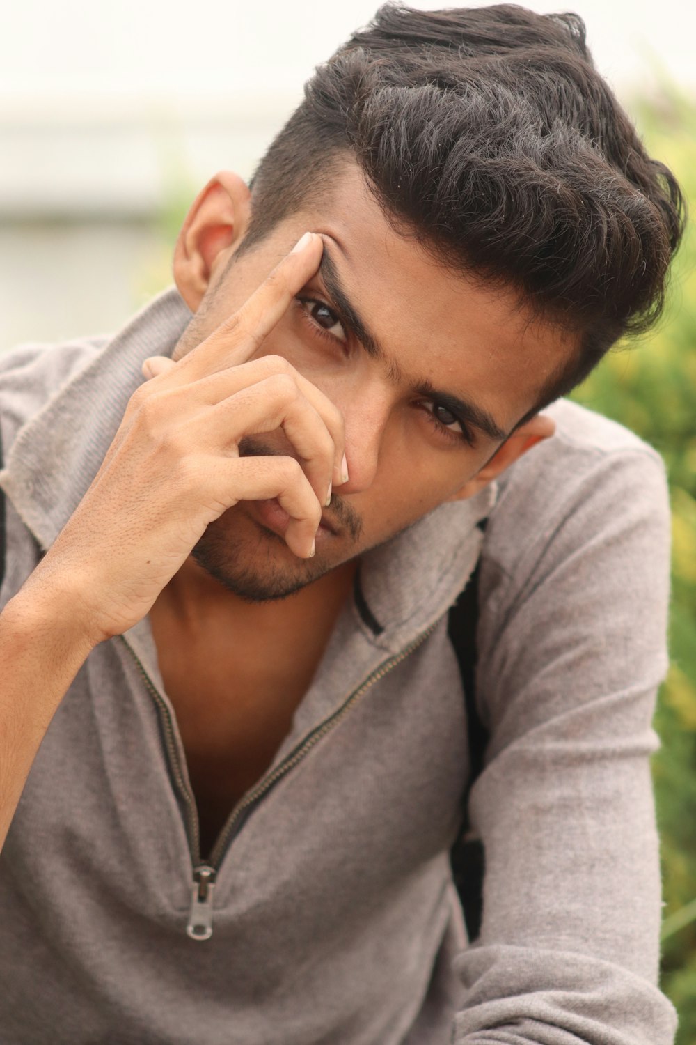 man in gray dress shirt touching his face