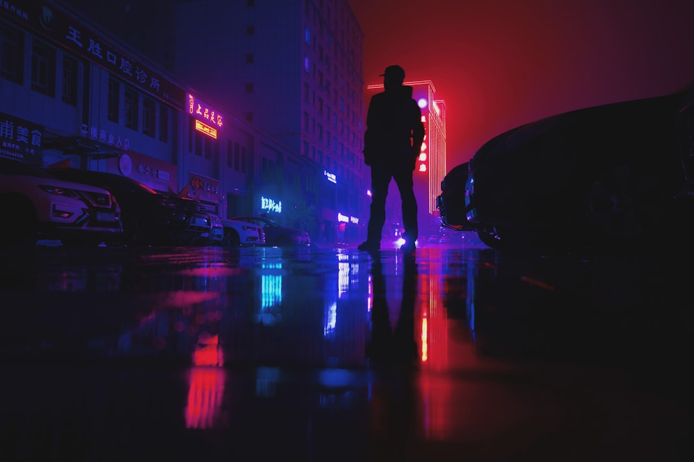 Un homme debout au milieu d’une rue la nuit