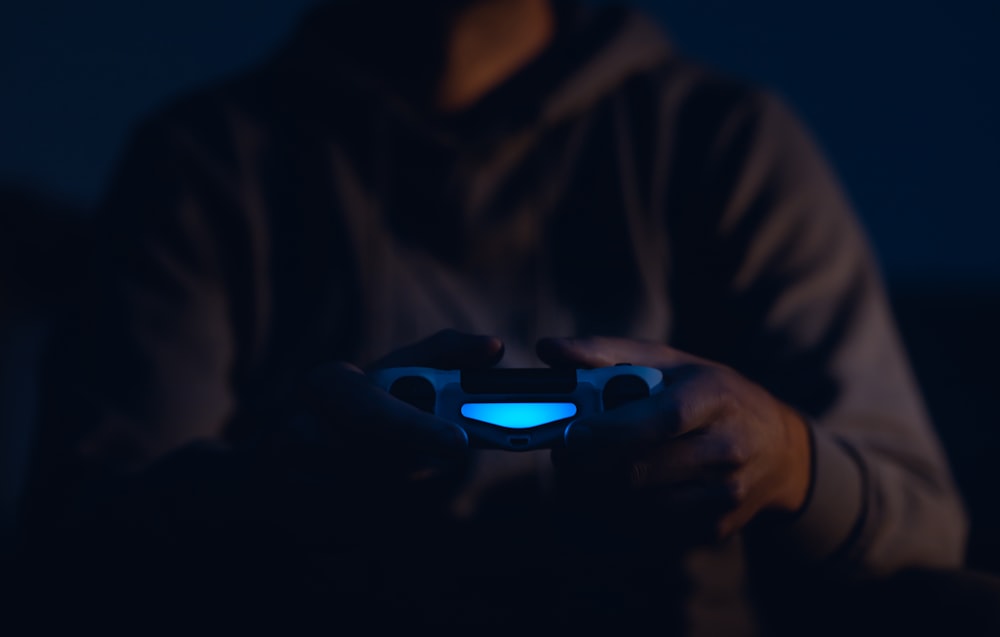 person wearing brown pullover using teal and black Sony PS4 Dualshock