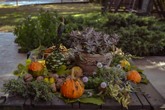 A child's hands arranging colorful autumn leaves and pinecones on a wooden table outdoors.