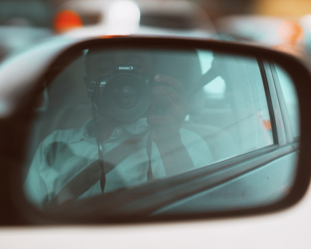 person taking photo of vehicle side mirror