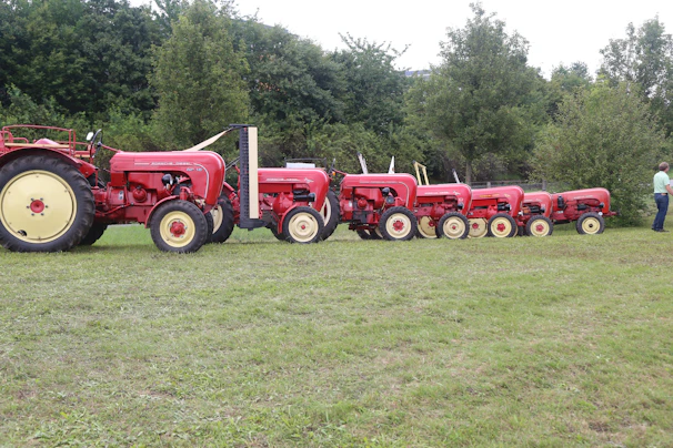 A vibrant display of various agricultural tractors and machinery lined up in a sunlit field.