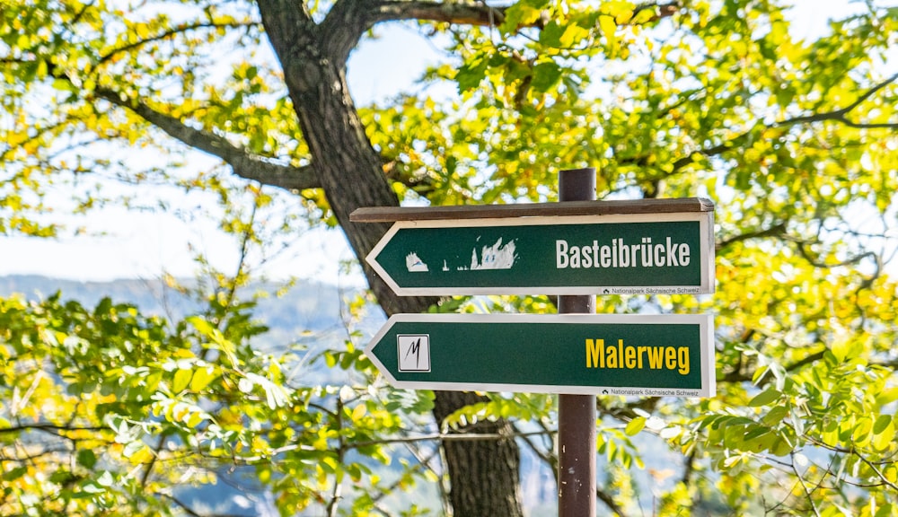 Bastelbrücke und Malerweg Wegweiser tagsüber am Pfosten in der Nähe des Baumes