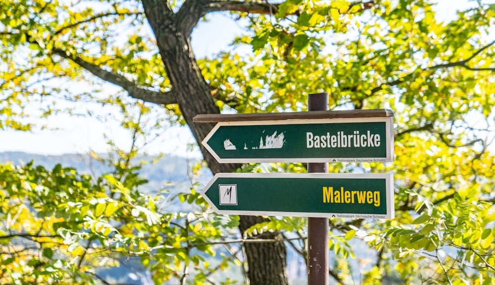 Bastelbrucke and Malerweg signboards on post near tree during day