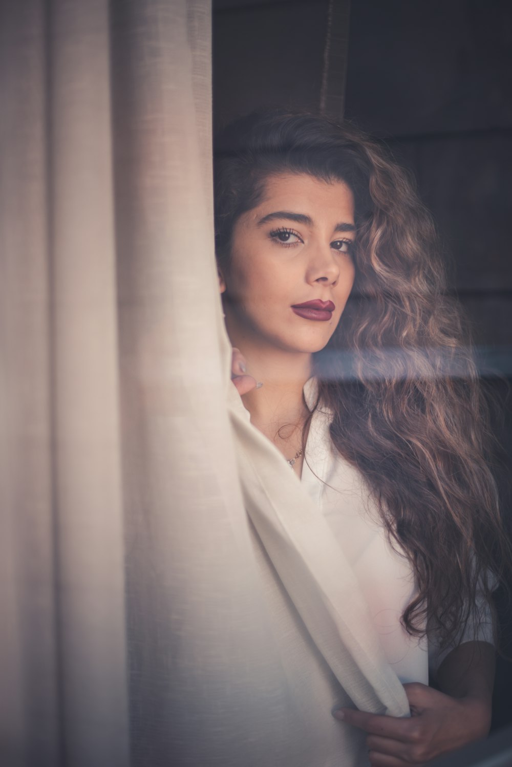 woman standing beside window curtain