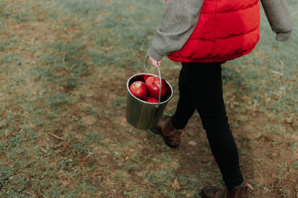 walking person holding bucket of apples