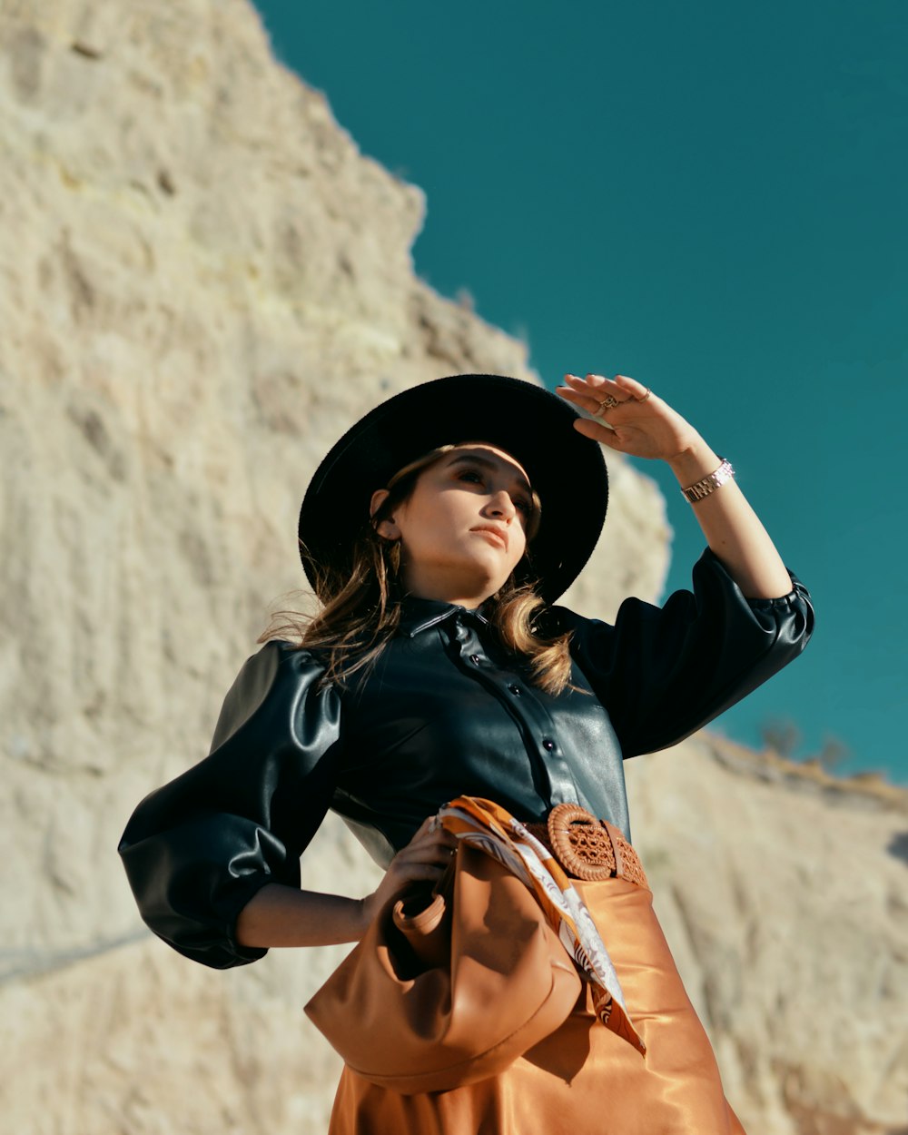 standing woman wearing black leather button-up jacket and black hat