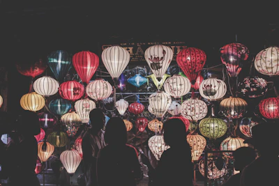A vibrant group of diverse conference attendees sharing stories and laughter under colorful lanterns in Thailand.