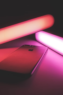 A stylish smartphone placed on a dark surface with glowing neon accents.