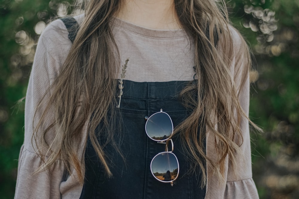 standing woman wearing gray crew-neck top with sunglasses