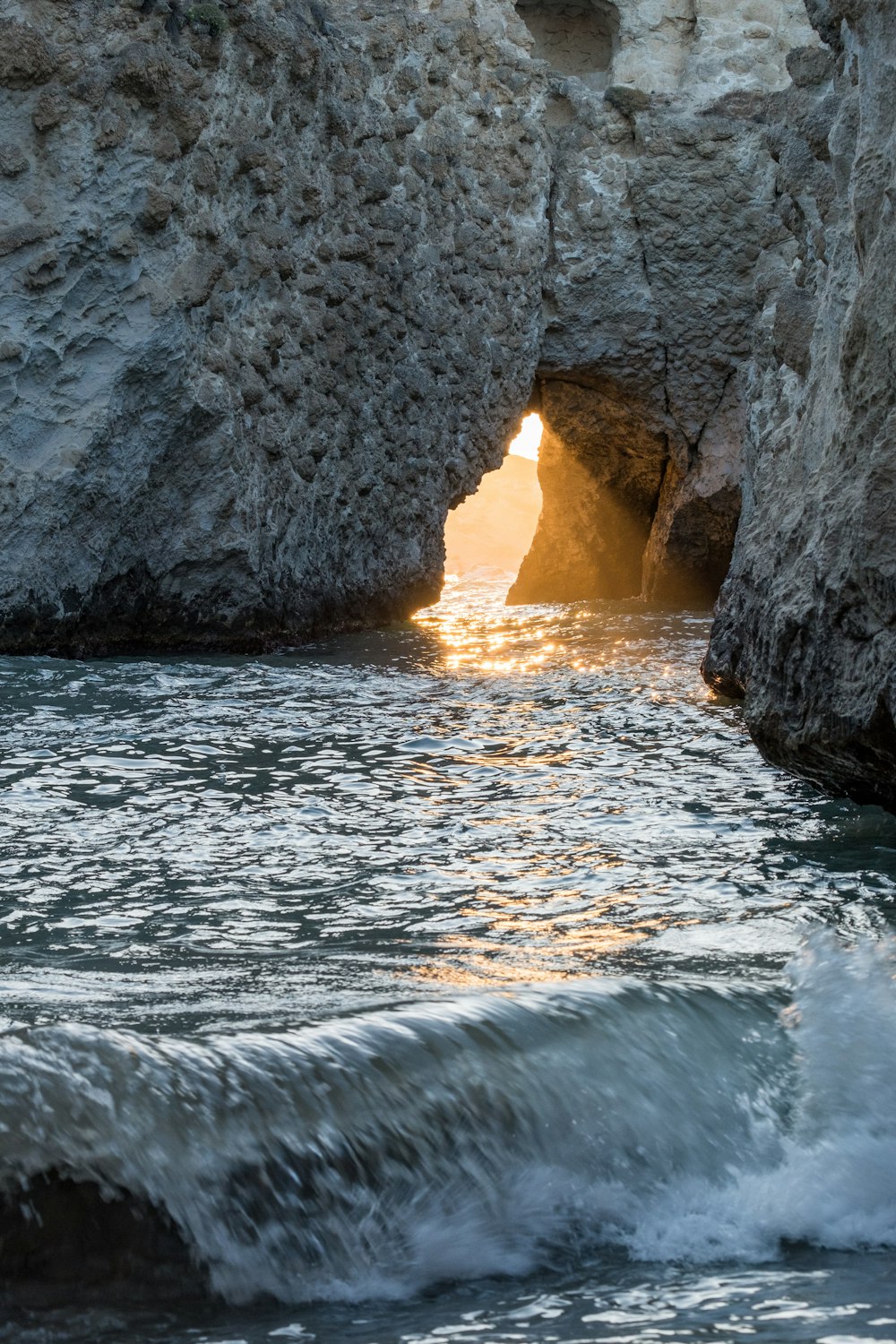 rocky mountain island with cave during day