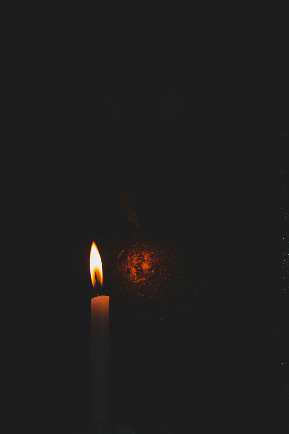 lighted taper candle in a dark room