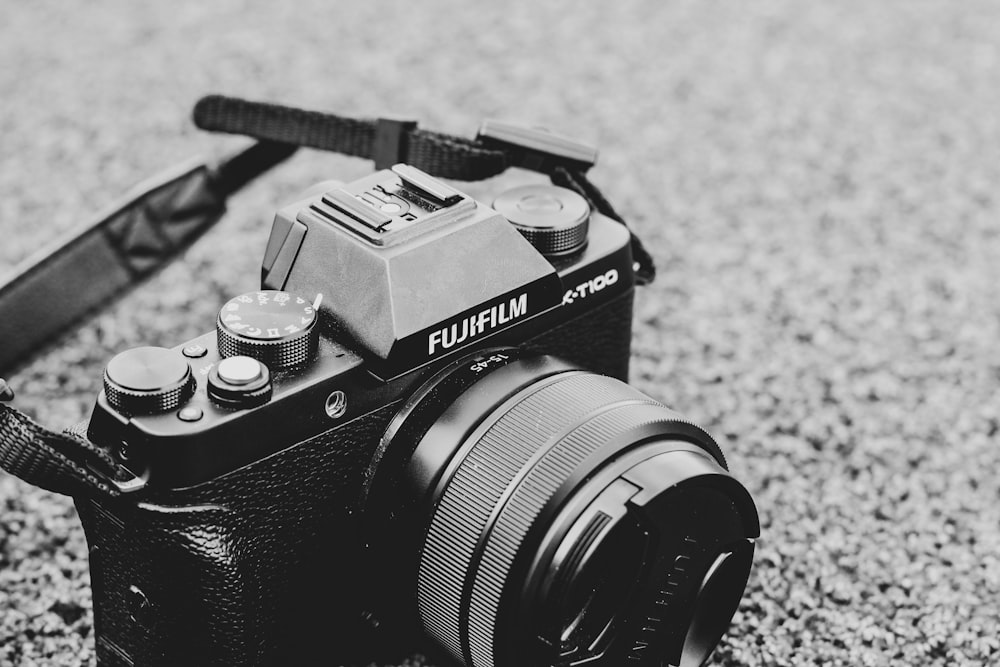 fotocamera reflex Fujifilm nera e grigia su superficie di cemento